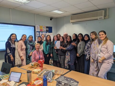 Learners in a classroom posing while holding a certificate