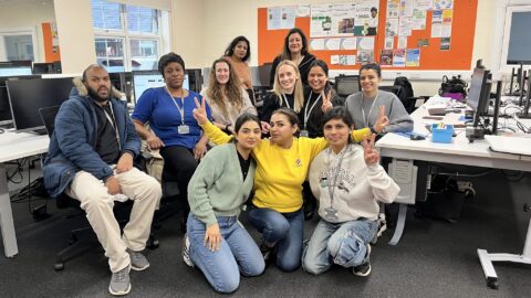 Learners posing for the camera doing the victory sign in front of their PCs