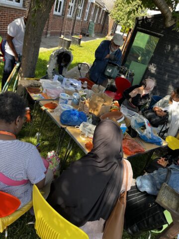 People outside, gathered around a table with various gardening items and tools.
