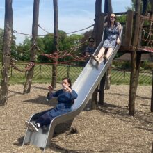 Two women going down a slide at a park