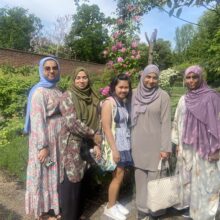 Five women posing for the camera at a park