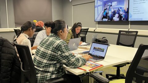 People sitting at a table, working on their laptops