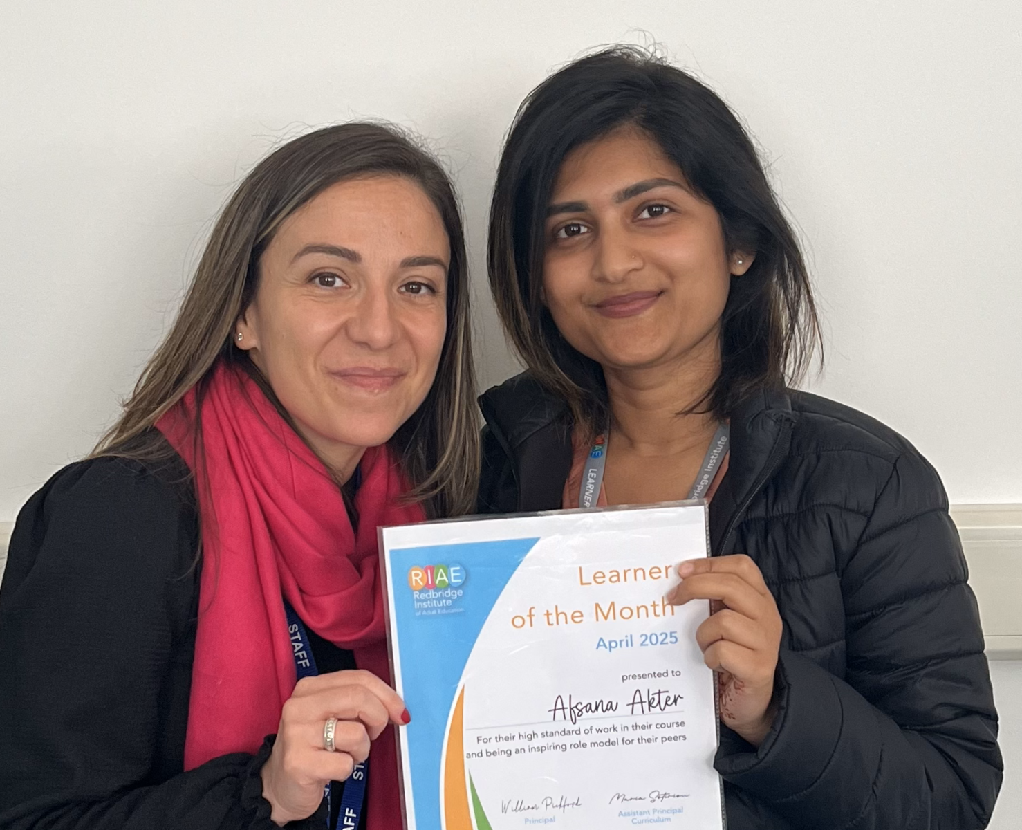 Two women posing for the camera, holding a certificate
