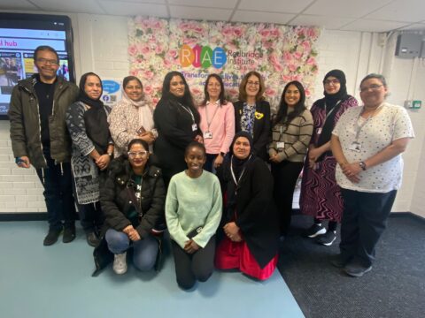 A group of learners posing for a photo in front of a wall of flowers