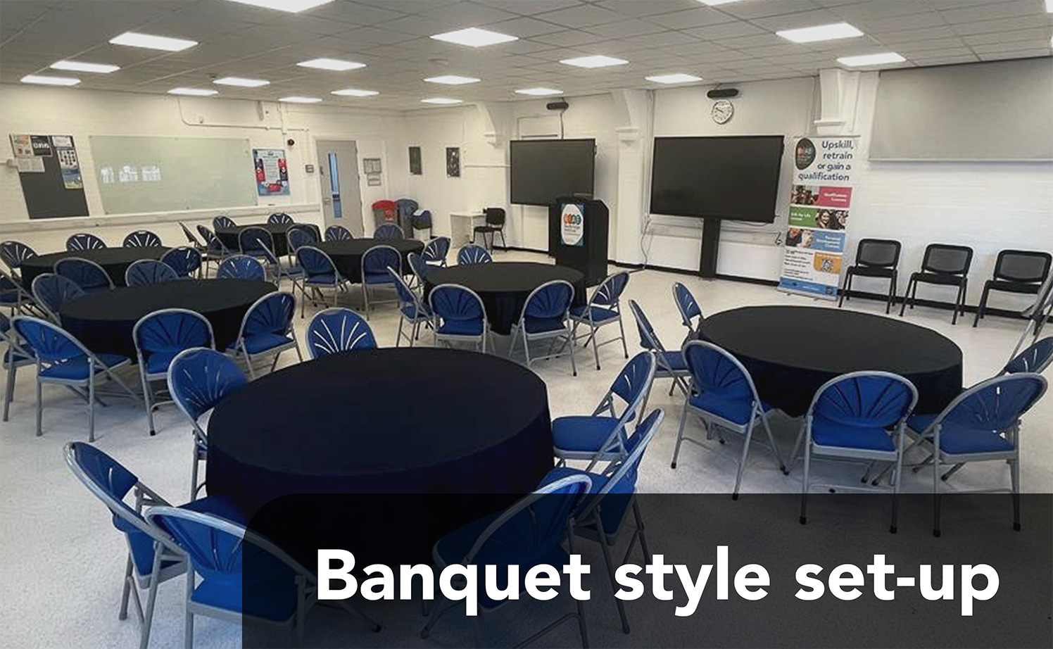 A room set up in banquet style, with large, round tables with tablecloths and chairs around them