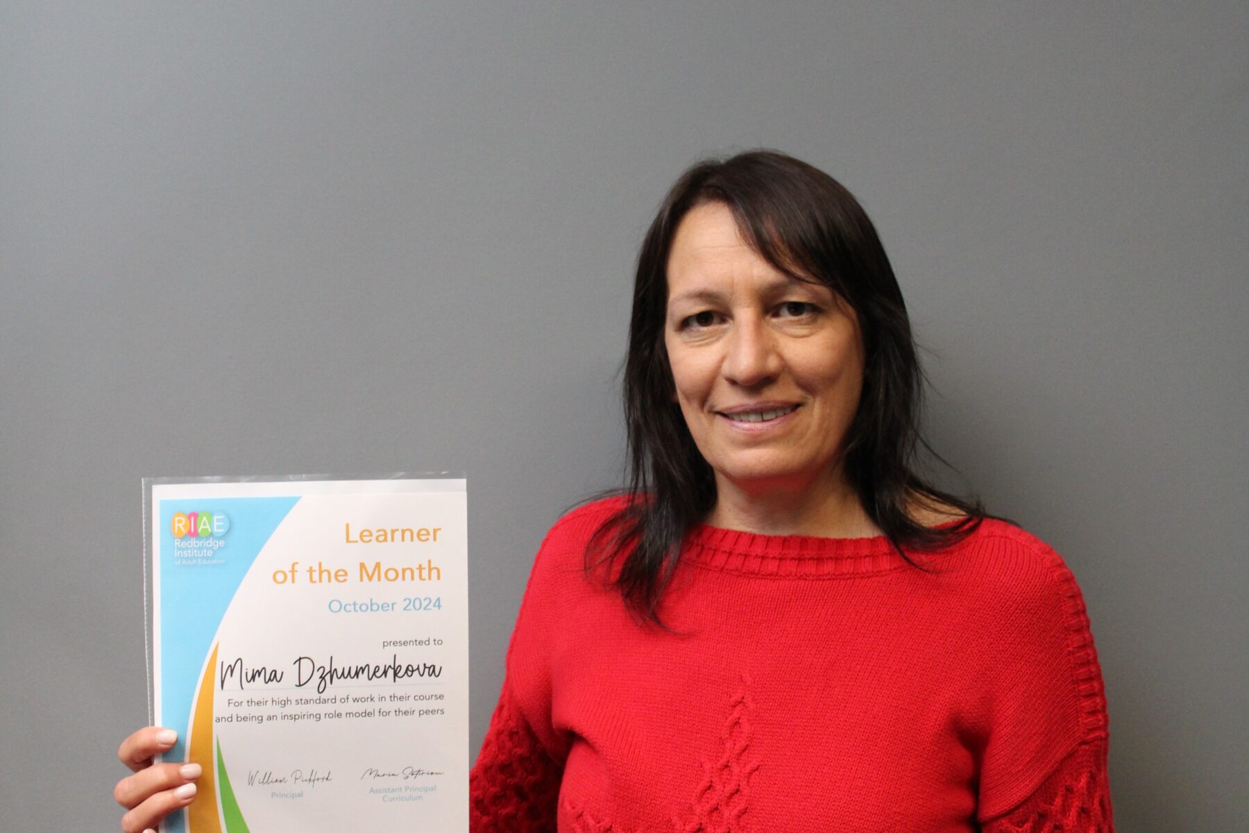 Learner in a red top holding a certificate